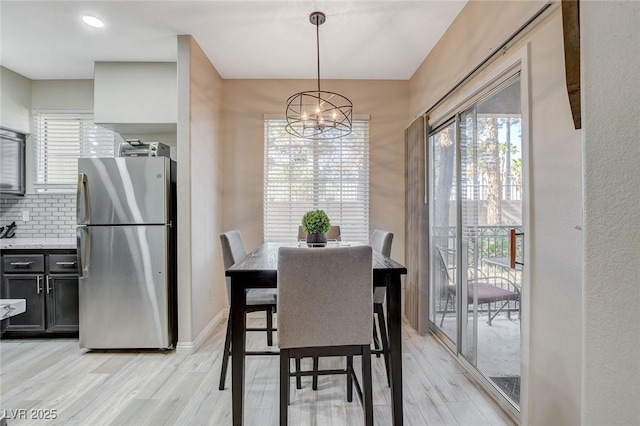 dining space featuring an inviting chandelier, light wood-style flooring, baseboards, and a healthy amount of sunlight