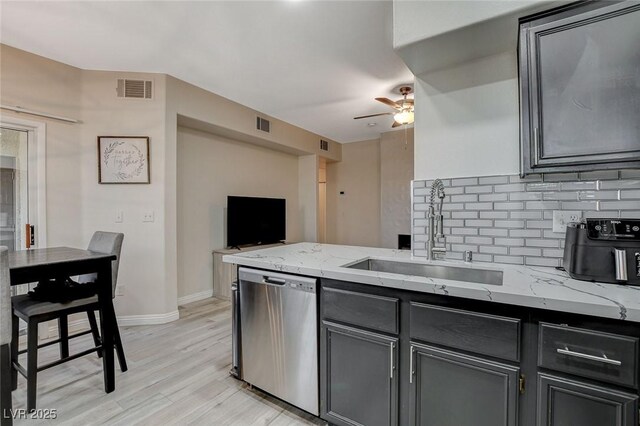 kitchen with a sink, dishwasher, ceiling fan, decorative backsplash, and light stone countertops