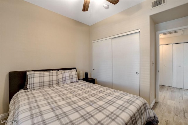 bedroom featuring a closet, light wood-style floors, visible vents, and baseboards