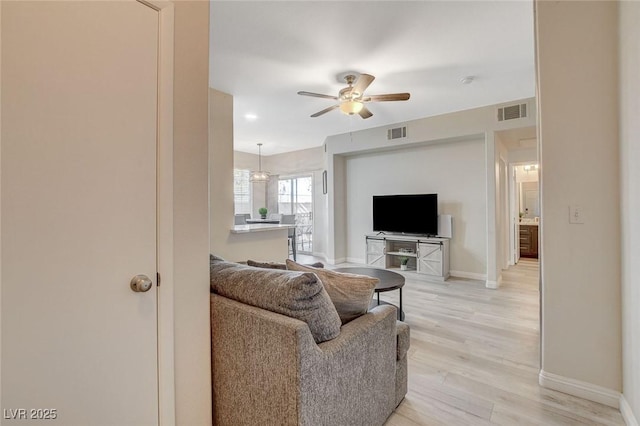 living area with a ceiling fan, baseboards, visible vents, and light wood-style floors
