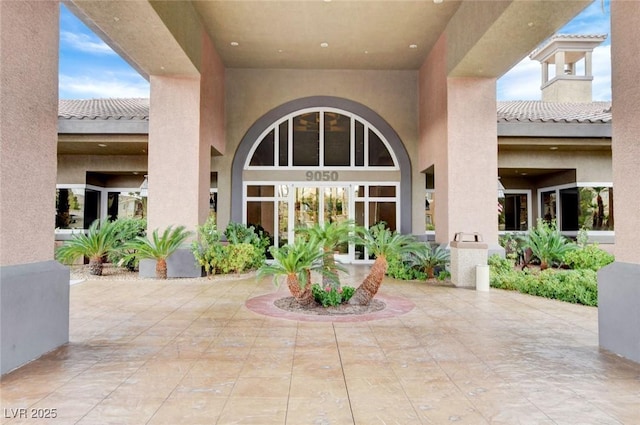 doorway to property with a tiled roof, stucco siding, and a patio area