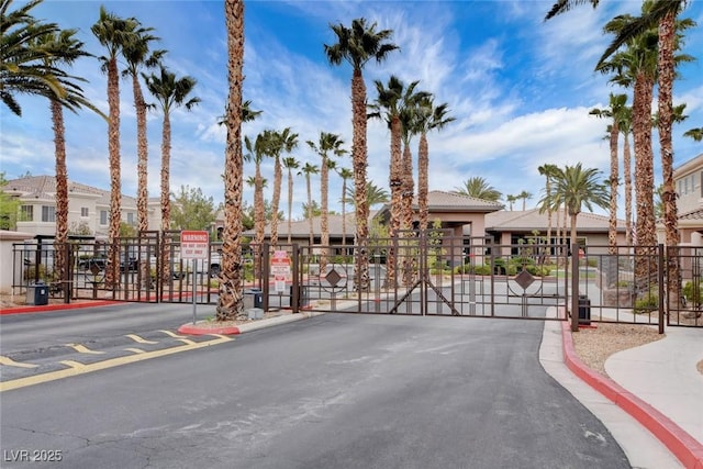 view of street featuring a gate, a gated entry, curbs, and a residential view