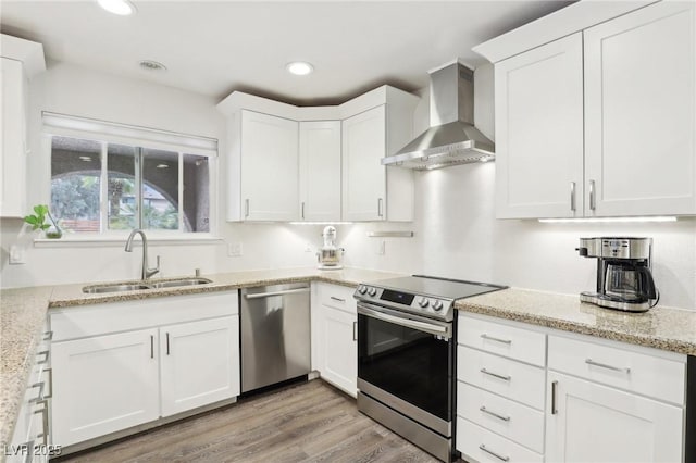 3155 Duneville St, Las Vegas, NV 89146 - kitchen featuring a sink, white cabinetry, wall chimney range hood, stainless steel appliances, and light wood-type flooring