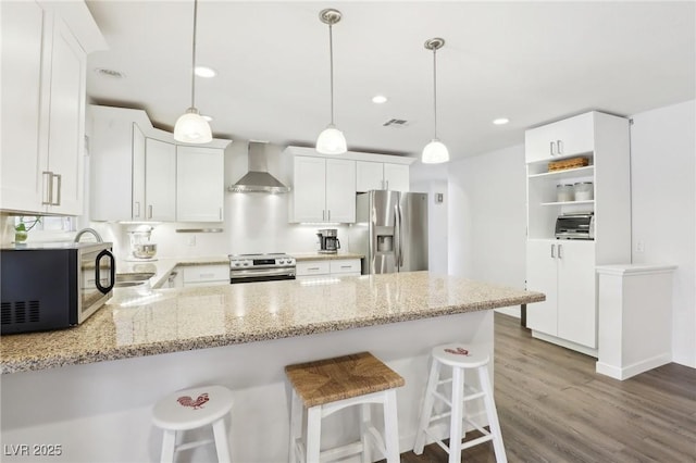 3155 Duneville St, Las Vegas, NV 89146 - kitchen with a peninsula, stainless steel appliances, wall chimney range hood, light stone counters, and dark wood finished floors