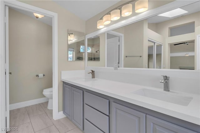 full bath with toilet, baseboards, and double vanity
