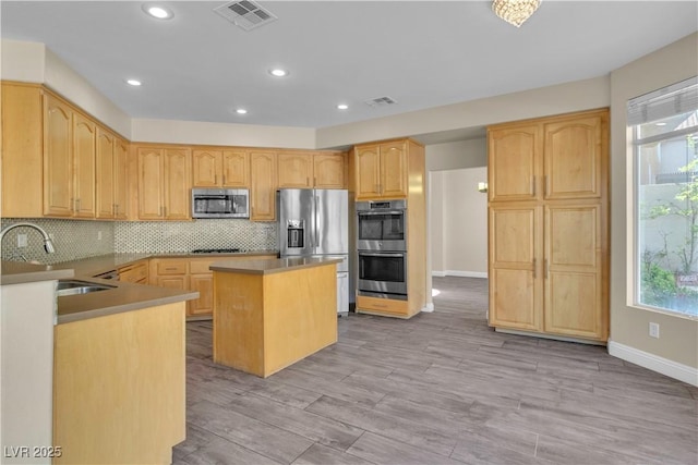 kitchen featuring appliances with stainless steel finishes, a sink, a kitchen island, plenty of natural light, and recessed lighting
