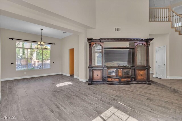 1717 Double Arch Ct, Las Vegas, NV 89128 - unfurnished living room featuring baseboards, a notable chandelier, visible vents, and wood finished floors