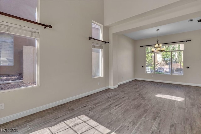 interior space featuring visible vents, wood finished floors, baseboards, and a notable chandelier