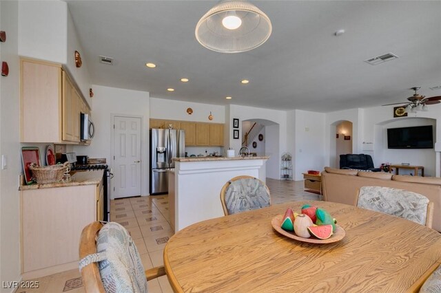 dining space featuring arched walkways, a ceiling fan, light tile patterned floors, and recessed lighting