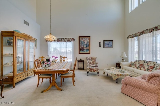 dining area with a high ceiling and carpet flooring