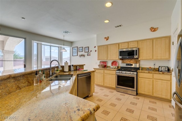 kitchen with stainless steel appliances, light brown cabinetry, a sink, light stone countertops, and light tile patterned flooring