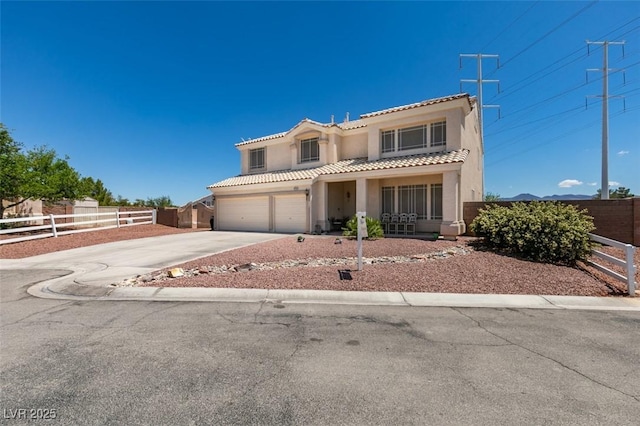 mediterranean / spanish-style home with stucco siding, a tiled roof, fence, and concrete driveway