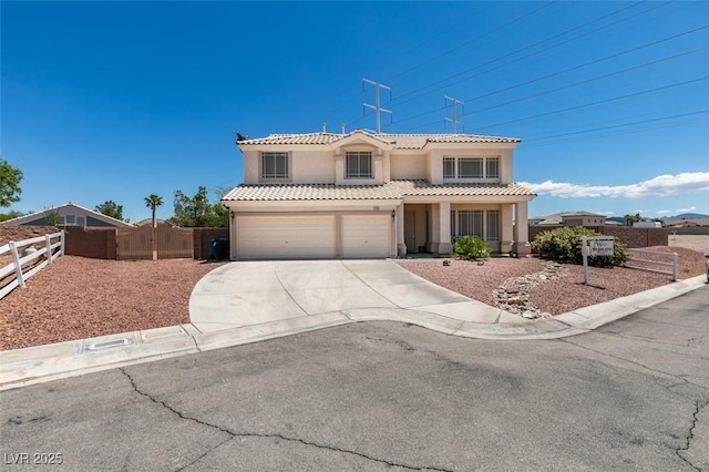 mediterranean / spanish home featuring concrete driveway, fence, stucco siding, a tiled roof, and a garage
