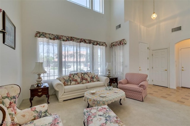 carpeted living room featuring a high ceiling and arched walkways