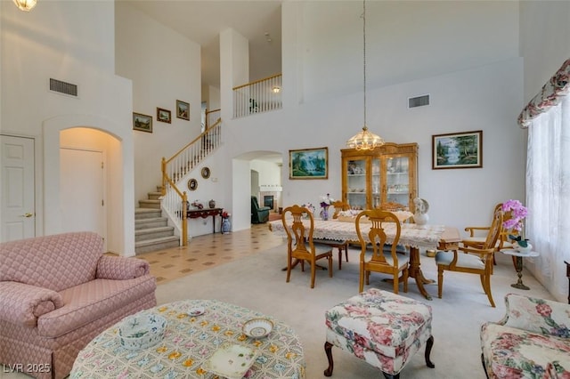 dining room with arched walkways, stairway, a high ceiling, and carpet flooring