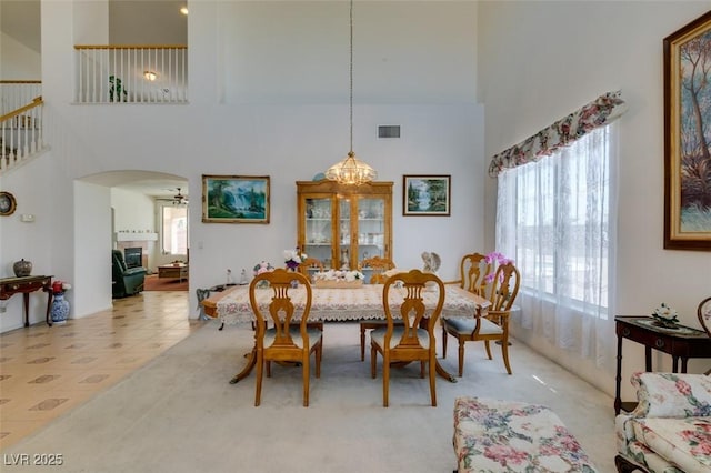 dining space featuring a high ceiling, arched walkways, and a ceiling fan