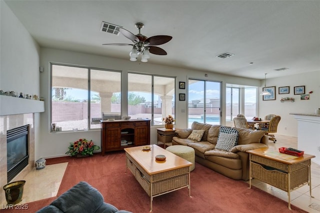 living room featuring a tile fireplace, healthy amount of natural light, and a ceiling fan