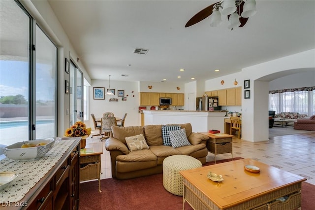 living area featuring ceiling fan, arched walkways, and recessed lighting