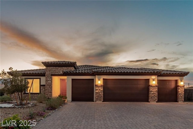 5741 N Park St, Las Vegas, NV 89149 - view of front of property with an attached garage, stone siding, stucco siding, a tile roof, and decorative driveway