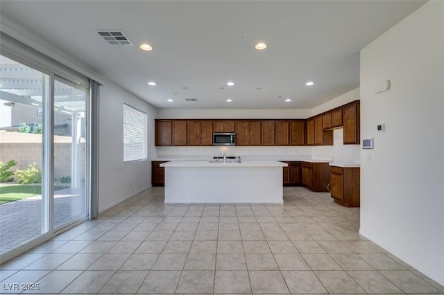 528 Sunny Pointe St, Henderson, NV 89011 - kitchen with stainless steel microwave, light countertops, recessed lighting, an island with sink, and baseboards