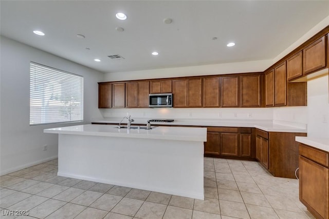 528 Sunny Pointe St, Henderson, NV 89011 - kitchen with stainless steel microwave, a sink, light countertops, brown cabinetry, and recessed lighting