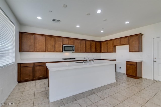 528 Sunny Pointe St, Henderson, NV 89011 - kitchen with stainless steel microwave, black stovetop, a kitchen island with sink, light countertops, and a sink