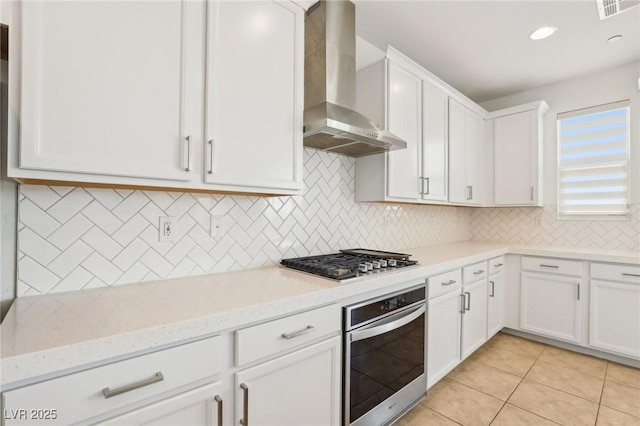 8724 Scalpay St, Las Vegas, NV 89166 - kitchen with appliances with stainless steel finishes, wall chimney range hood, white cabinetry, light stone counters, and decorative backsplash