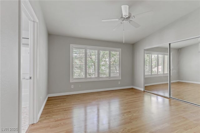 unfurnished bedroom with a ceiling fan, a closet, baseboards, vaulted ceiling, and wood finished floors