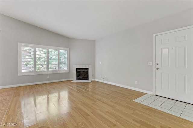 unfurnished living room featuring light wood finished floors, baseboards, and a tile fireplace