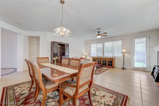 dining area with light tile patterned flooring, plenty of natural light, ceiling fan with notable chandelier, and visible vents