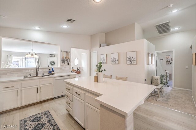 8136 Shady Glen Ave, Las Vegas, NV 89131 - kitchen featuring white dishwasher, decorative backsplash, light countertops, white cabinetry, and a chandelier