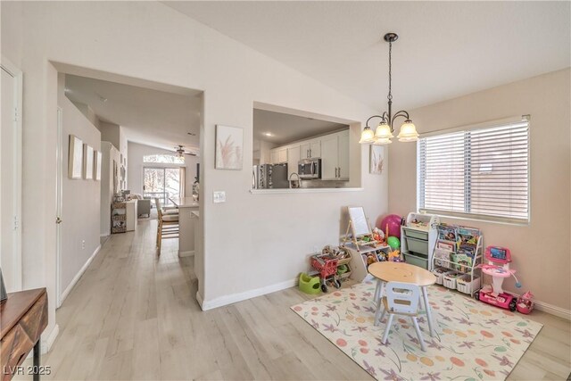 game room with light wood-style floors, vaulted ceiling, baseboards, and a notable chandelier