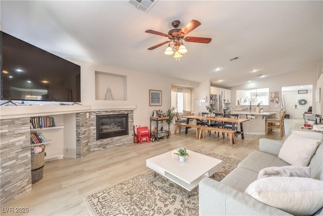 8136 Shady Glen Ave, Las Vegas, NV 89131 - living room with ceiling fan, vaulted ceiling, light wood-style flooring, and a stone fireplace