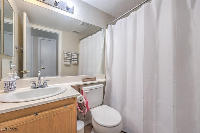 bathroom with vanity, toilet, and visible vents