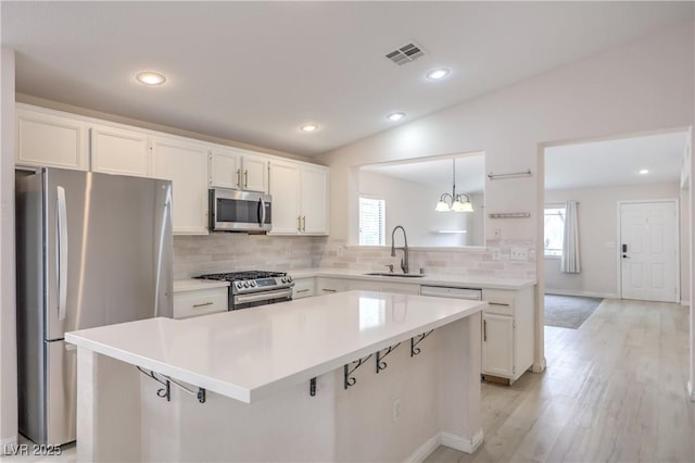 8136 Shady Glen Ave, Las Vegas, NV 89131 - kitchen with appliances with stainless steel finishes, decorative backsplash, a center island, white cabinets, and light wood-type flooring