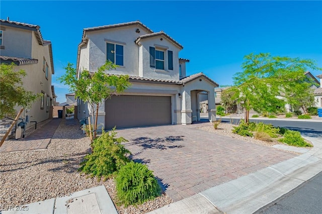 mediterranean / spanish-style home featuring driveway, stucco siding, a tile roof, and a garage