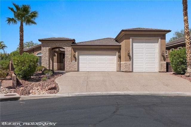 653 Paloma Cir, Mesquite, NV 89027 - view of front facade with driveway, a tiled roof, an attached garage, stucco siding, and stone siding