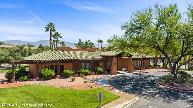 653 Paloma Cir, Mesquite, NV 89027 - view of front of home with a mountain view, a tiled roof, stucco siding, and a front lawn