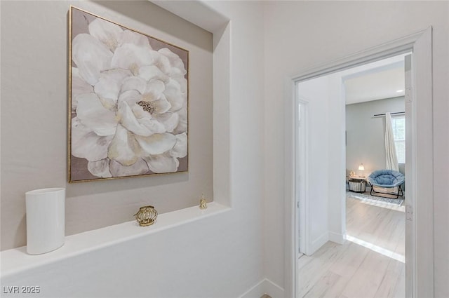 hall featuring baseboards and light wood-type flooring