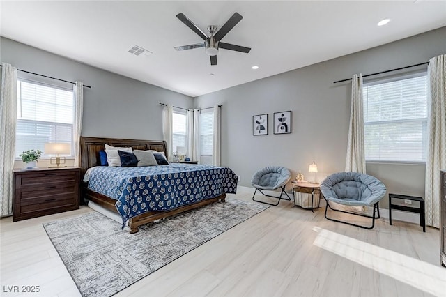 bedroom with ceiling fan, multiple windows, light wood finished floors, and visible vents