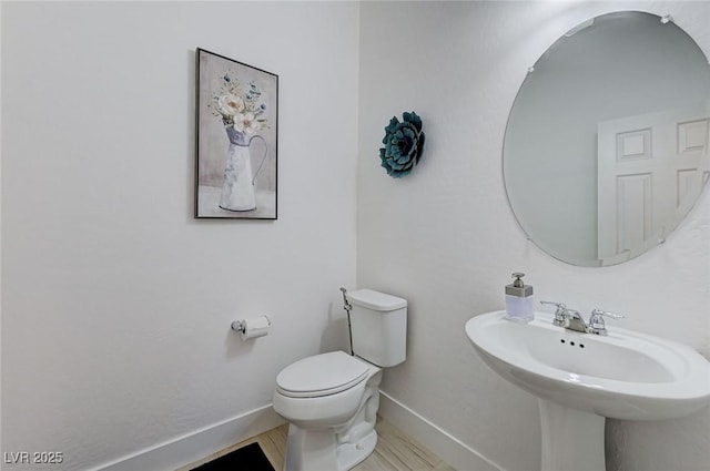 bathroom featuring baseboards, toilet, and a sink