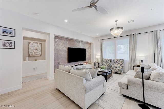 living room featuring ceiling fan with notable chandelier, visible vents, baseboards, light wood-style floors, and recessed lighting