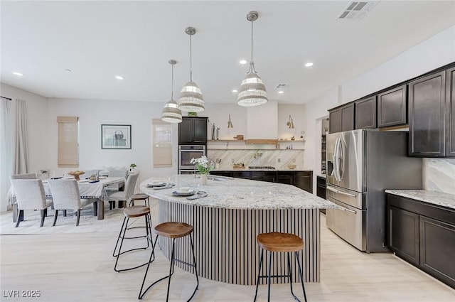 kitchen with a kitchen bar, appliances with stainless steel finishes, dark brown cabinets, and visible vents