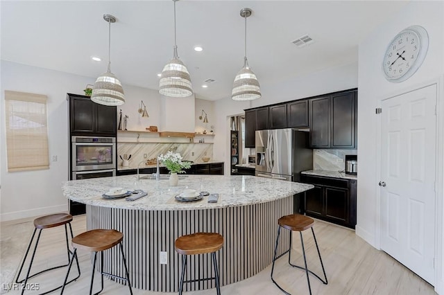 kitchen featuring light stone countertops, baseboards, visible vents, a kitchen breakfast bar, and appliances with stainless steel finishes