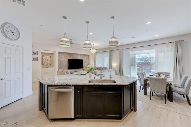kitchen featuring a sink, a kitchen island with sink, visible vents, dishwasher, and light stone counters
