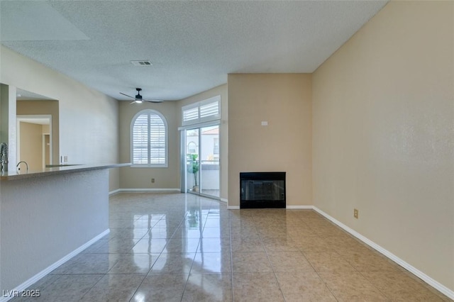 3150 Soft Breezes Dr Unit 2030, Las Vegas, NV 89128 - unfurnished living room with a textured ceiling, baseboards, ceiling fan, a glass covered fireplace, and light tile patterned flooring