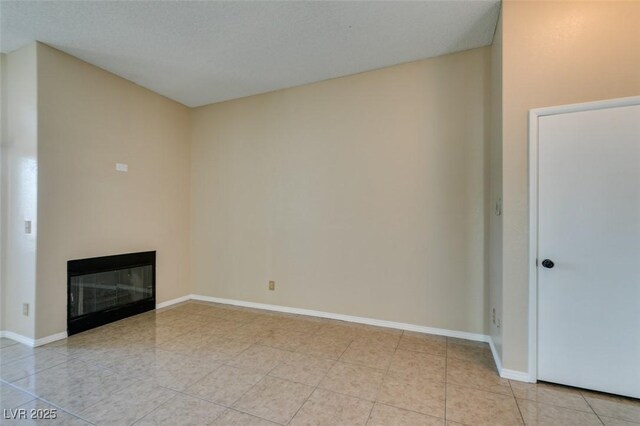 3150 Soft Breezes Dr Unit 2030, Las Vegas, NV 89128 - unfurnished living room featuring baseboards, a glass covered fireplace, and light tile patterned floors