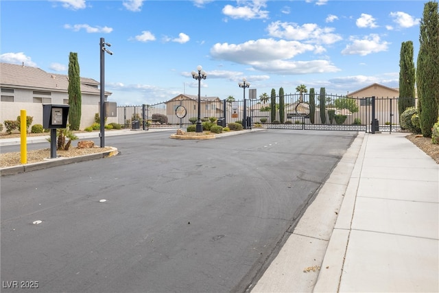 view of road featuring a gate, curbs, and sidewalks
