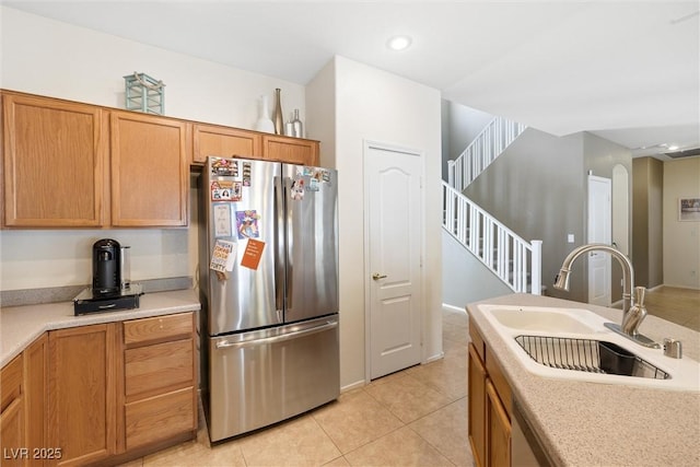 kitchen featuring a sink, freestanding refrigerator, light tile patterned flooring, and light countertops