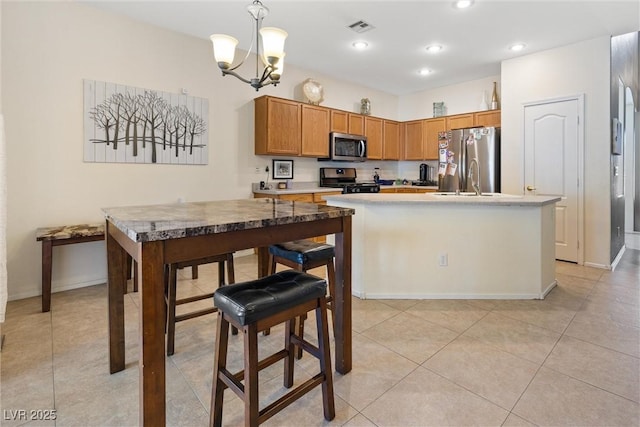 kitchen with pendant lighting, a kitchen island with sink, visible vents, appliances with stainless steel finishes, and a chandelier